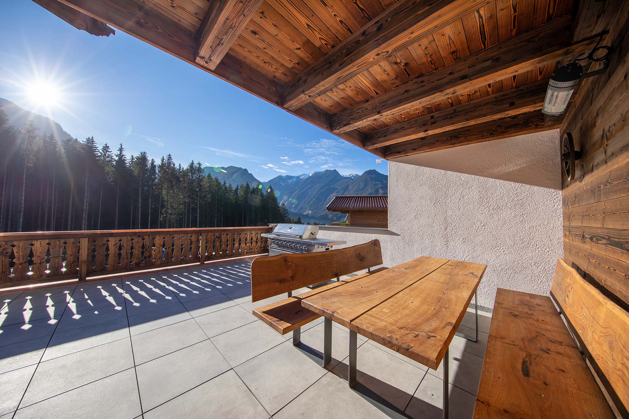 Balkon mit Gasgrill und massiven Holztisch und Holzbänken